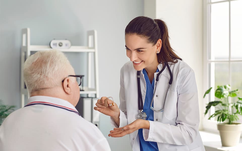 An audiologist talking about the pros and cons of hearing aids to an elderly man