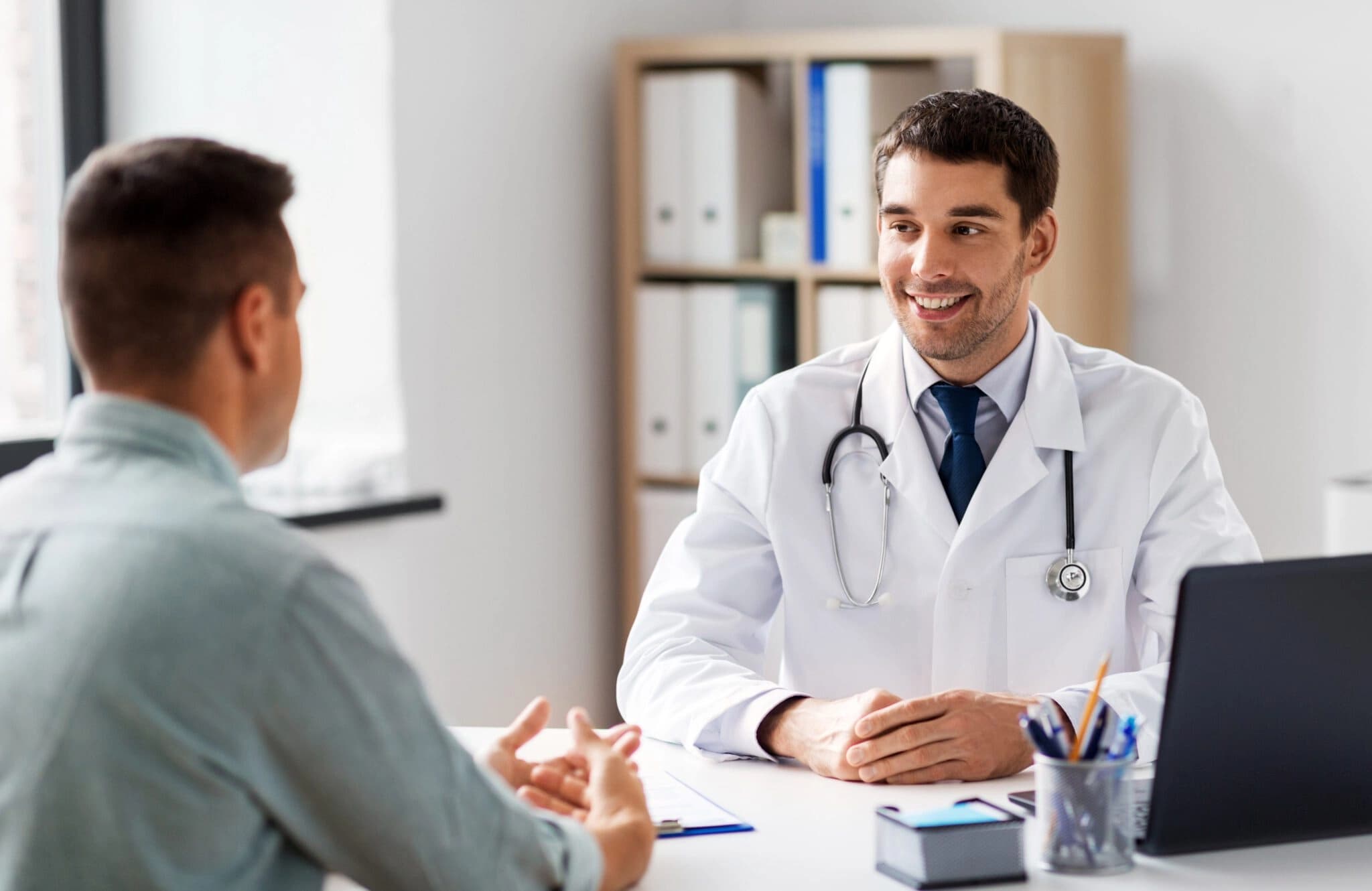 Doctor speaking to patient across a desk with a smile on his face
