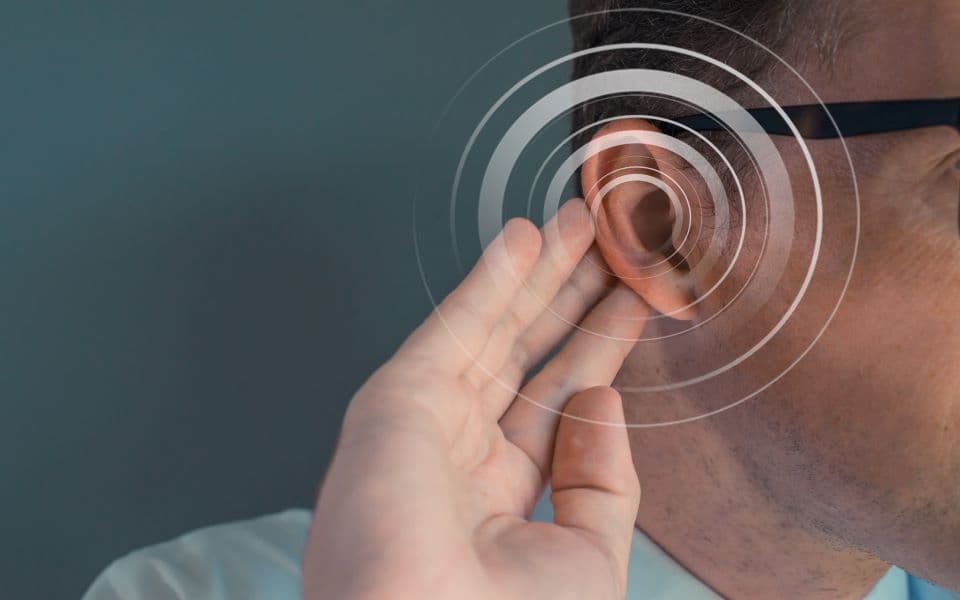 Sensorineural hearing loss concept - Man with his hand on his ear & a circular overlay over his ear