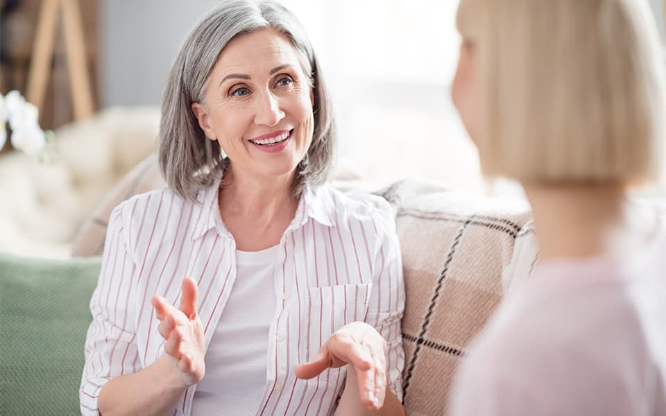 2 women sitting on a sofa talking to each other