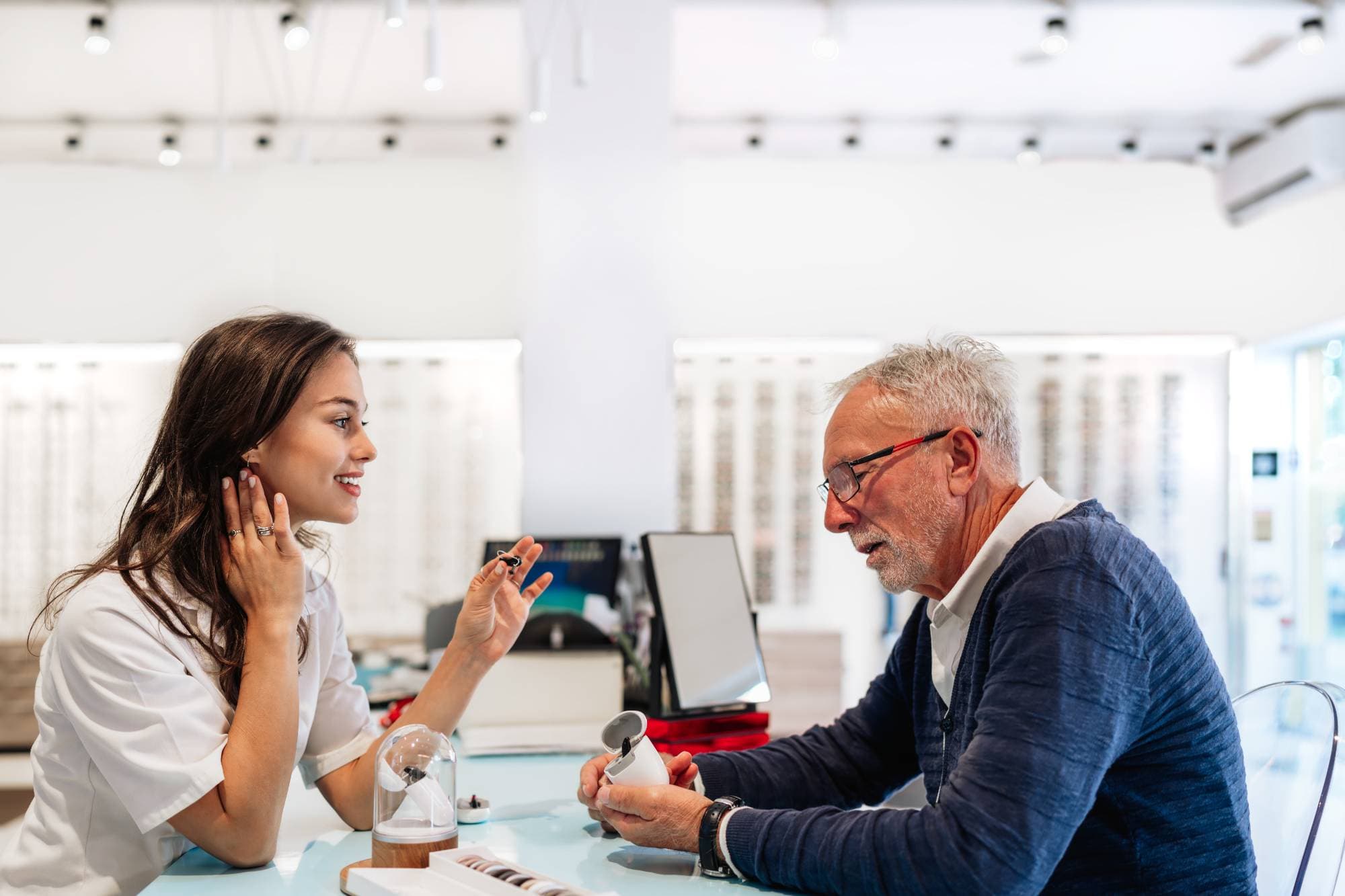 a young lady helping an older man purchase hearing aids