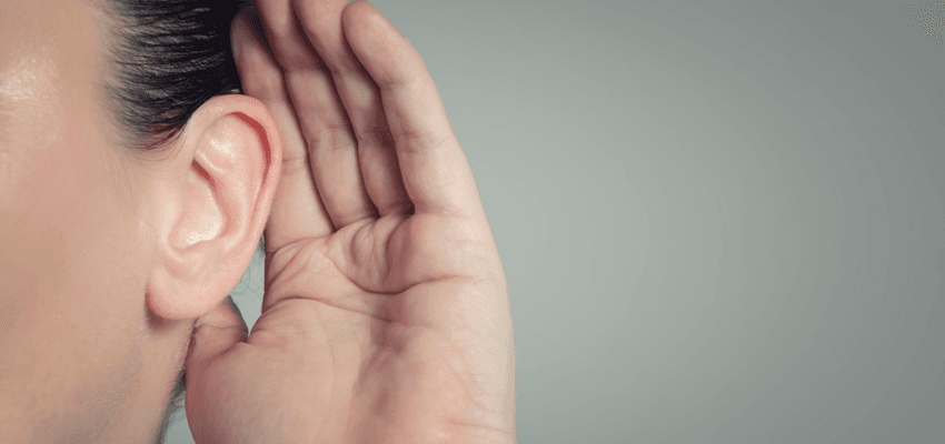 woman holding hand up to ear to hear better