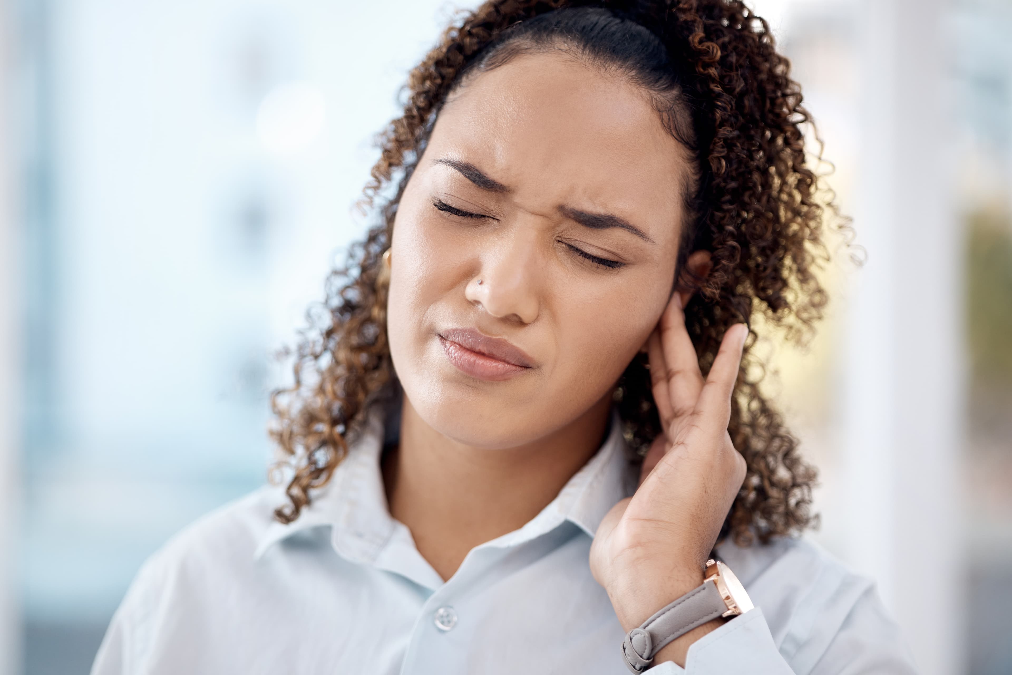 Woman holding her ear due to discomfort caused by otosclerosis
