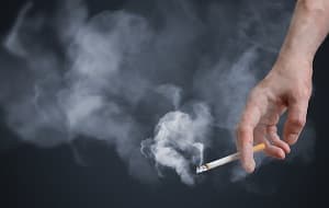 Hand holding smoking cigarette