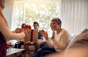 Little girl surprising her grandmother with a Christmas gift
