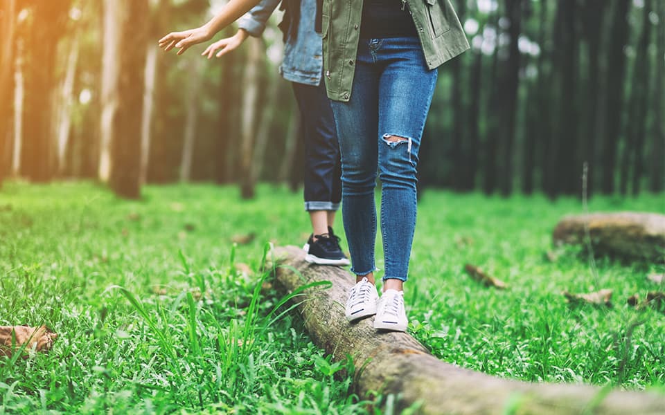 Travelers balancing on a log in the woods while hiking