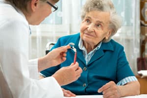 Audiologist explaining hearing aids to an older female patient