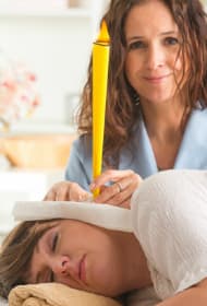 Female audiologist performing ear wax removal technique on women patient