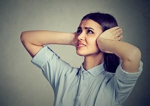 Stressed woman covering her ears as if experiencing hearing loss