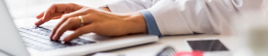 Doctors hands typing on a laptop