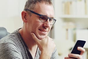 man wearing hearing aid looking at smartphone