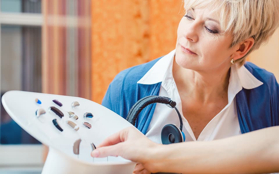 Senior woman with impairment choosing hearing aid for the first time in a shop