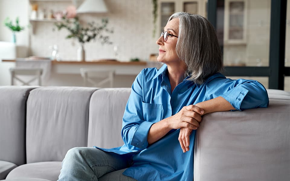 Calm relaxed mature older woman relaxing sitting on a couch at home.